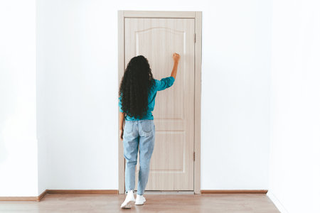 Woman Knocking on a Wooden Door in a Bright and Minimalistic Roomの写真素材