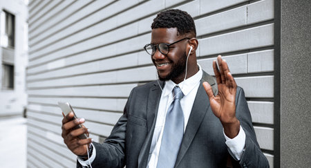Man in Suit Smiles While Using Smartphone, Listening to Music Outdoorsの写真素材