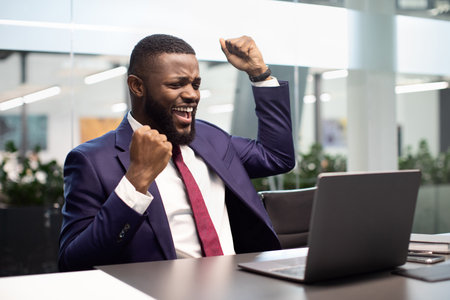 Emotional african american businessman sitting in front of laptopの写真素材