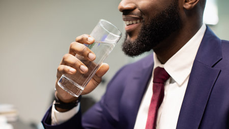Unrecognizable bearded black man in suit drinking waterの写真素材