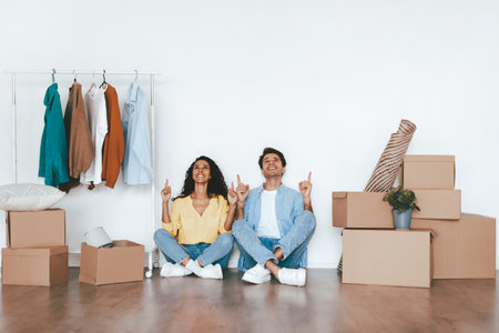 Couple Celebrating Their New Home With Playful Gestures Among Moving Boxes and Clothesの写真素材