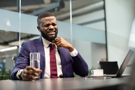 Black manager untying his suit, office interiorの写真素材