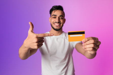 Happy Young Arab Man Promoting Electronic Money With Credit Card in Neon Light Background
