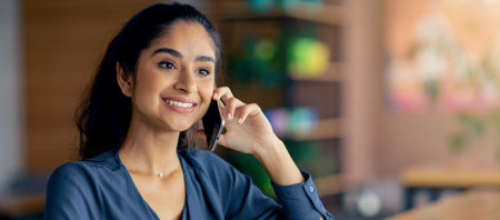 Smiling Woman Talking on the Phone in a Cozy Cafe Setting During the Dayの写真素材