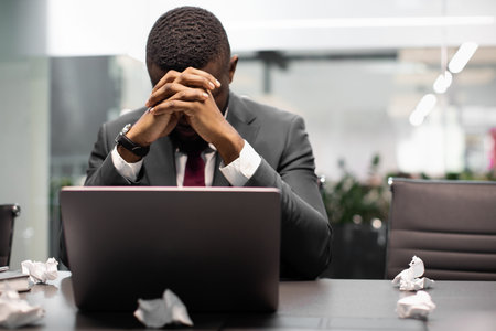 Tired black manager working on laptopの写真素材