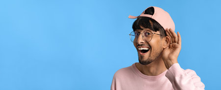 Happy Man Listening Intently Against a Bright Blue Background in Casual Attireの写真素材