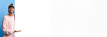 Man in Pink Sweater Stands Against Blue Wall and Gestures With a Smileの写真素材