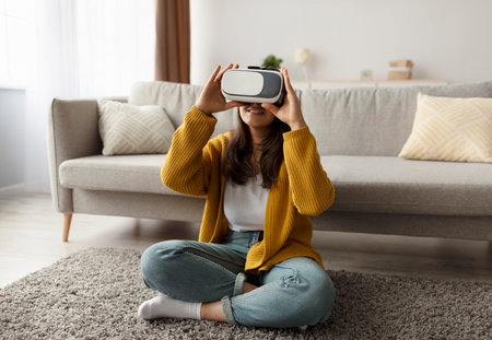 Young Arab Woman Enjoys Virtual Reality Experience While Sitting on Living Room Floorの写真素材