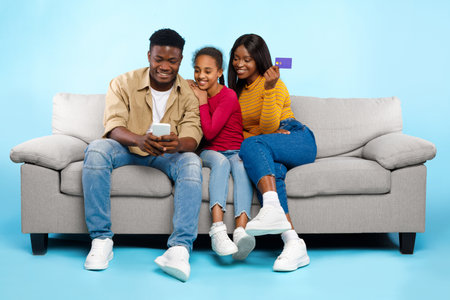 Happy Black Family Enjoying Online Shopping Together on a Couchの写真素材