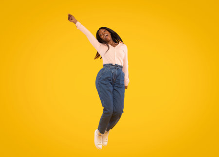 Celebrating Joy With a Joyful Leap Against a Bright Yellow Backgroundの写真素材