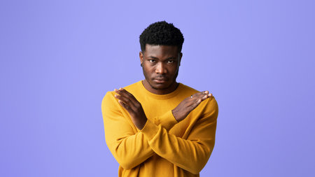 Man in Yellow Sweater Shows Crossed Arms Against a Purple Background