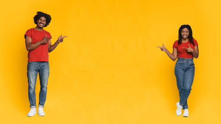 Two Friends Point and Smile in Front of a Bright Yellow Background During a Fun Photo Sessionの写真素材