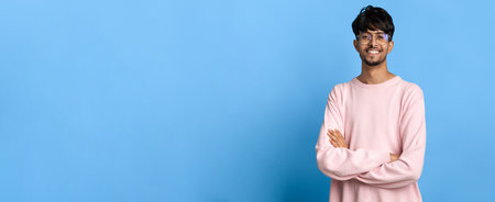Young Man Smiling Against a Blue Background During a Casual Momentの写真素材