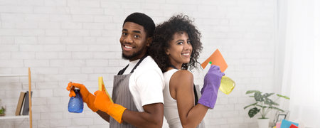 Happy African American couple holding detergents during cleaning at homeの写真素材
