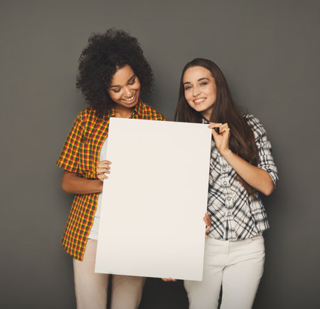 Two girlfriends holding blank white bannerの写真素材