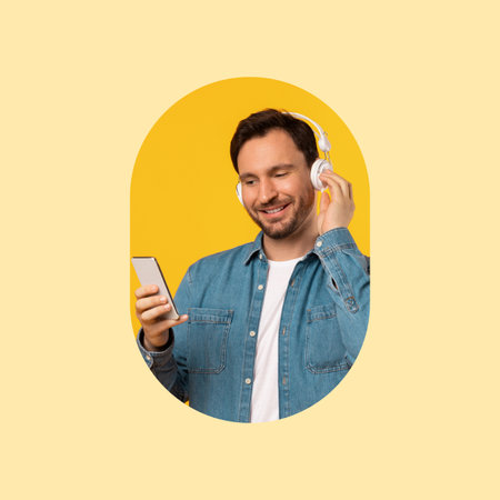 A man smiles while listening to music through headphones and looking at his smartphone. The bright yellow background creates a cheerful atmosphere for the moment.の写真素材