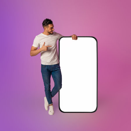 Happy Young Arab Man Sharing Mobile App Recommendation With Large Blank Screenの写真素材