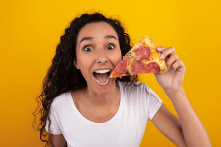 Young Woman Celebrating With a Slice of Pizza in a Bright Studio Settingの写真素材