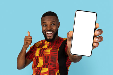 African Man In Traditional Costume Holding Blank Smartphone And Showing Thumb Upの写真素材