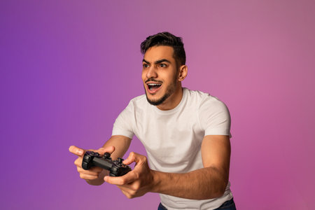 Young Arab Man Shows Excitement While Gaming With Joystick Under Neon Lightsの写真素材
