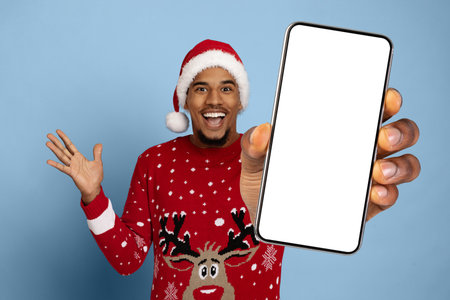 Happy Man Wearing Christmas Attire Shows Smartphone With Blank Screen During Holiday Seasonの写真素材