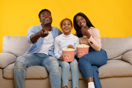 Happy Family Enjoys Movie Night Together on a Cozy Sofa With Snacks and Laughterの写真素材