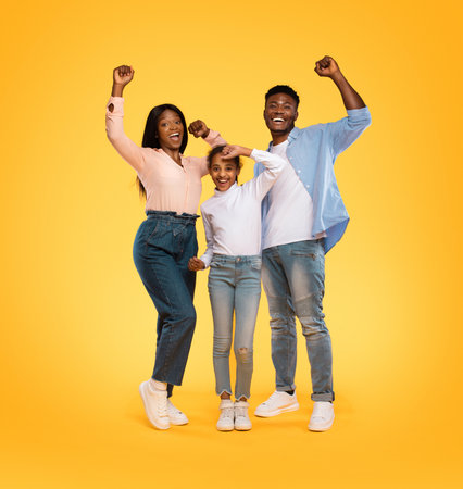 Excited Family Celebrating Success Together in a Vibrant Yellow Settingの写真素材