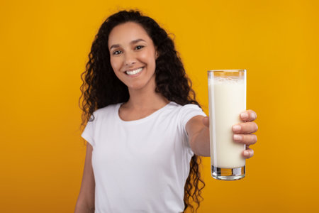 Young Woman Happily Recommends Milk for Healthy Nutrition in Studio Settingの写真素材