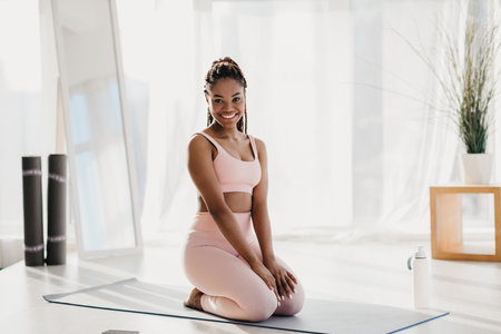 Young Black Woman Enjoys a Break While Exercising at Home on Yoga Matの写真素材
