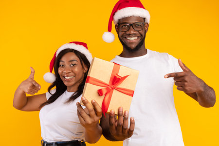 Happy Couple Celebrating Christmas With a Gift Against a Bright Yellow Backgroundの写真素材