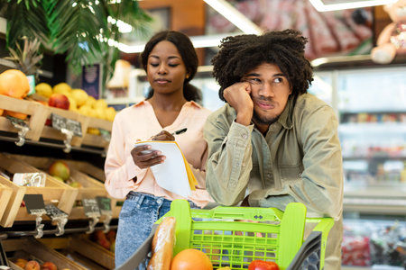 Grocery Shopping Experience Leads to Bored Wait for a Man as Woman Takes Notesの写真素材