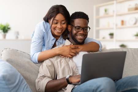 Happy Couple Enjoying Time Together on Sofa While Working Remotely With Laptopの写真素材