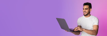 Smiling Young Arab Man Working on Laptop During Video Call in Vibrant Neon Light Settingの写真素材