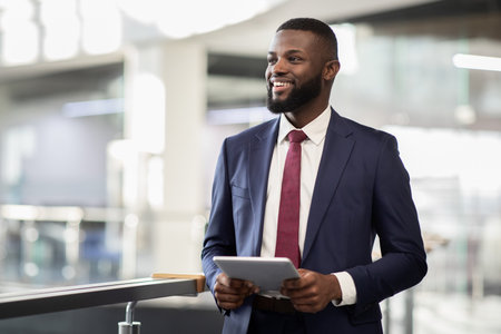 Cheerful black manager with digital tablet walking by officeの写真素材