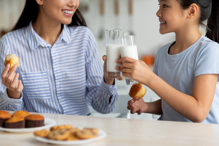 Enjoying Milk and Bonding in the Kitchen, Asian Girl and Mother Share a Joyful Momentの写真素材