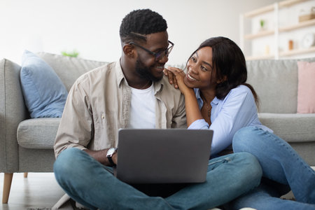 Happy Black Couple Enjoying Online Shopping for Furniture in Cozy Living Roomの写真素材