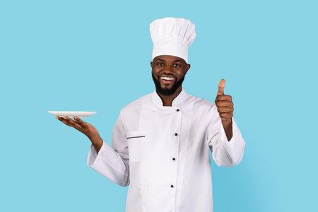 Handsome Black Chef In Uniform Holding Empty Plate And Showing Thumb Upの写真素材