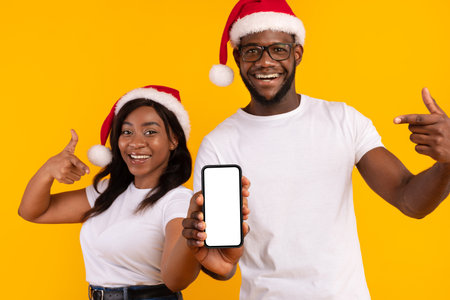 Black Couple Promoting Christmas Offer With Blank Phone Screen in Studio Settingの写真素材