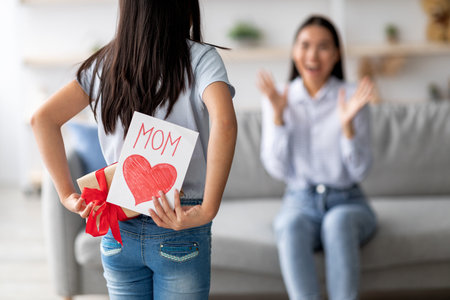 Girl Surprises Her Mom With a Special Gift and Card for Mothers Day Celebration at Homeの写真素材