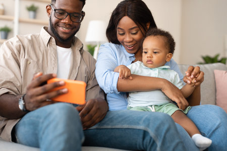 Family Time at Home With Baby Watching Cartoons on Smartphone and Video Chatting With Grandparentsの写真素材