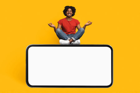 Man Meditating Above a Blank Screen Against a Bright Yellow Background in a Modern Settingの写真素材
