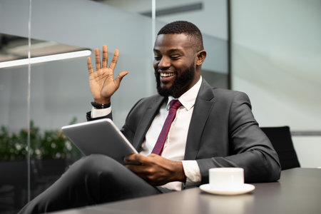 Happy black businessman having video chat, using digital tabletの写真素材