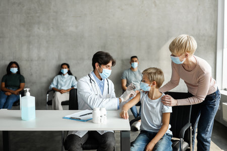Blonde boy schooler getting vaccination at clinicの写真素材