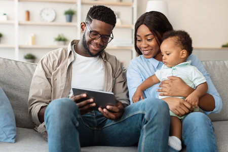 Happy African American Family Enjoying Educational Content on Tablet at Home Togetherの写真素材