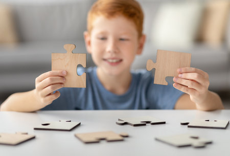Smiling Preteen Redhead Boy Enjoys Solving Wooden Puzzles While Home Aloneの写真素材