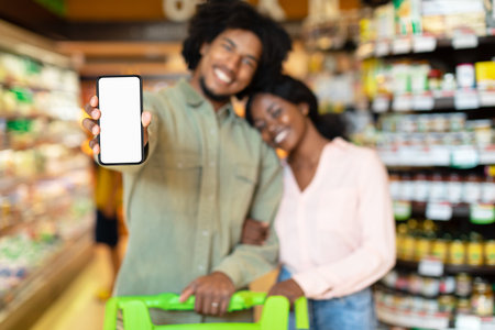 Couple Happily Shopping Together and Showing Smartphone While Enjoying Grocery Store Visitの写真素材