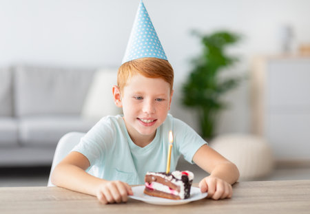 Cheerful Boy Celebrating Birthday at Home With Cake and Candle During COVID-19 Quarantineの写真素材