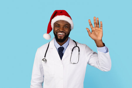 Smiling Black Doctor In Santa Hat Waving Hand At Cameraの写真素材