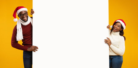 African Couple Celebrates New Year With Festive Hats and Offers in Yellow Studio Backgroundの写真素材