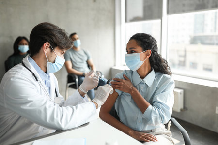 Female patient looking at handsome doctor while getting vaccinationの写真素材